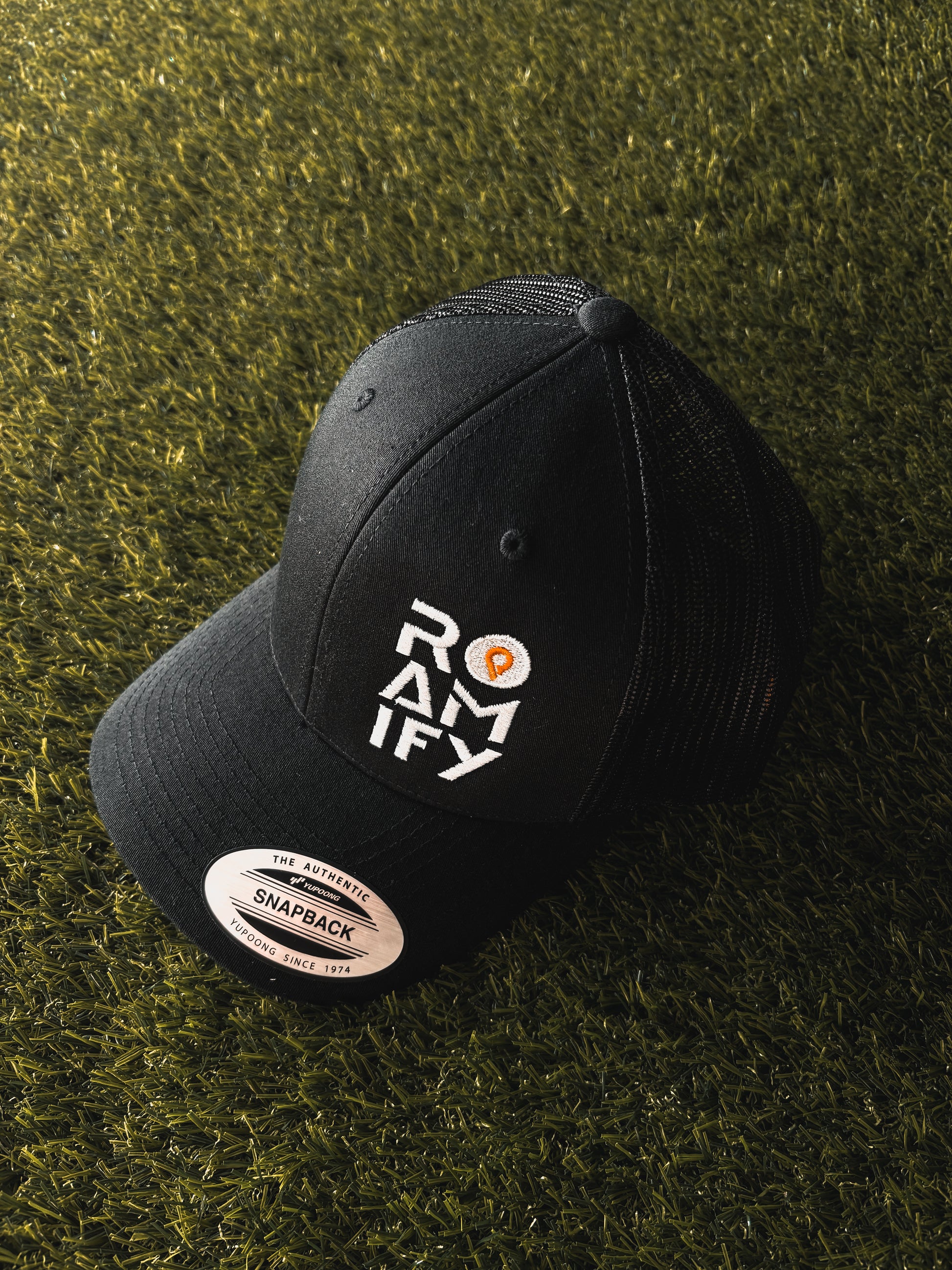 Black cap with 'ROAMIFY' logo on a grassy background