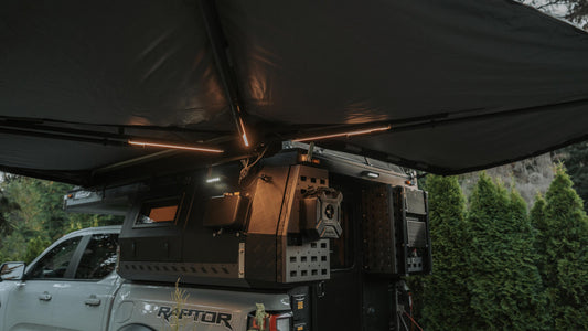 Truck with a roof tent and off-road vehicle in a forest setting
